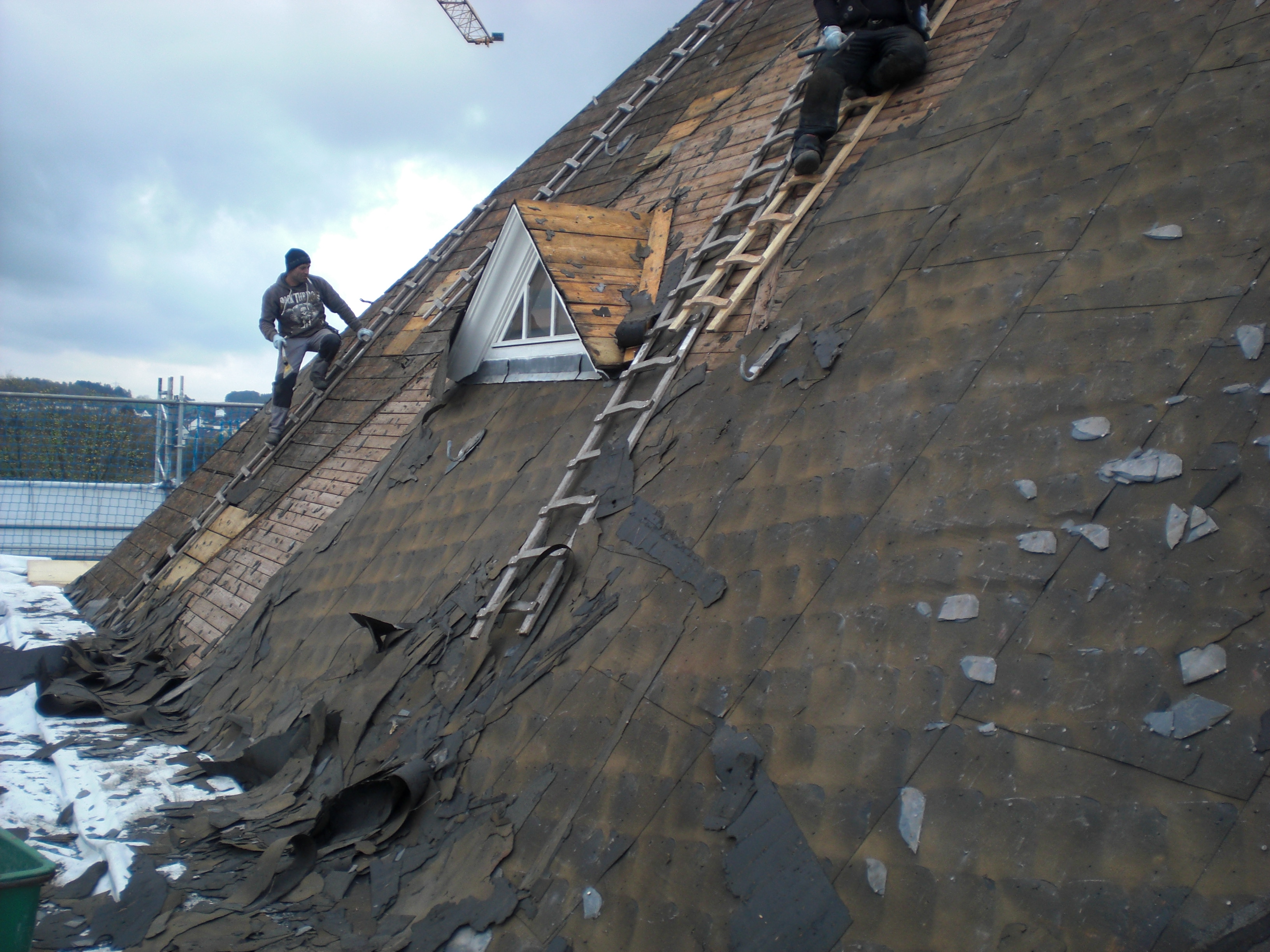 Abriss der alten Schieferdeckung auf der nächsten Dachfläche auf dem Hauptgebäude