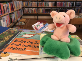 Glücksschweinchen aus Plüsch auf einem Stapel Bücher